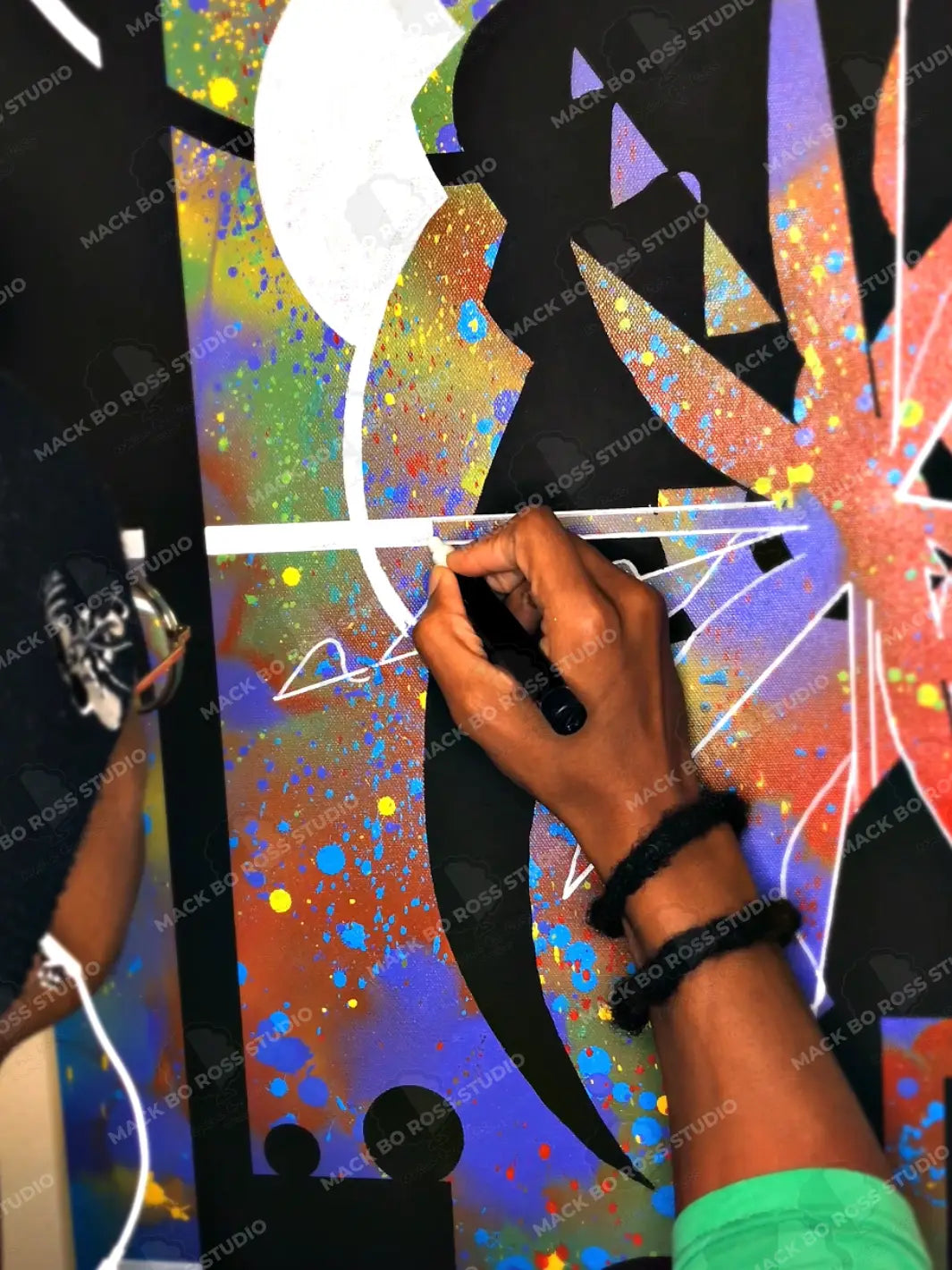 Artist Mack Bo Ross using Posca markers to create a canvas painting.