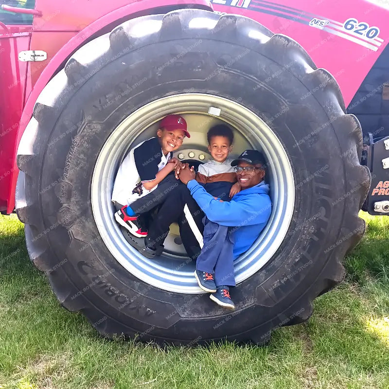 Father and sons sitting in tractor tire at the Dane county dairy breakfast 