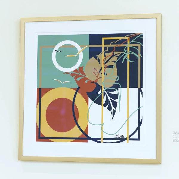 Framed abstract artwork with geometric shapes and colors on a white wall.
